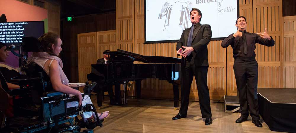 Sydney Opera House Access Launch to male singers, one Deaf and singing in front a piano and audience on stage.