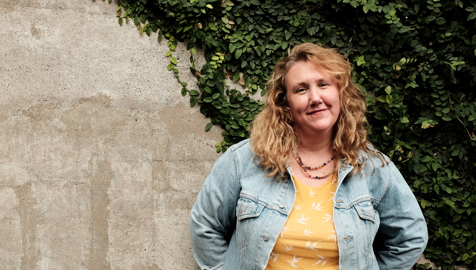 Octapod: Riona Tindal is standing with her back to a stone wall partially covered with a vine. Photo by Susan Wright