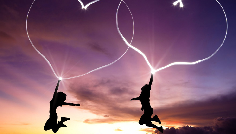 Documentary: Two figures are jumping in the air and have outlines of hearts extending from their extended arms and hands