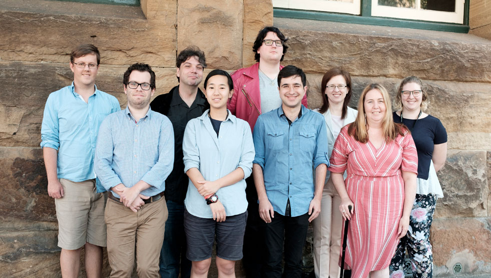 Createability interns: Nine people are standing in a group and looking at the camera. They have their backs to a stone wall.