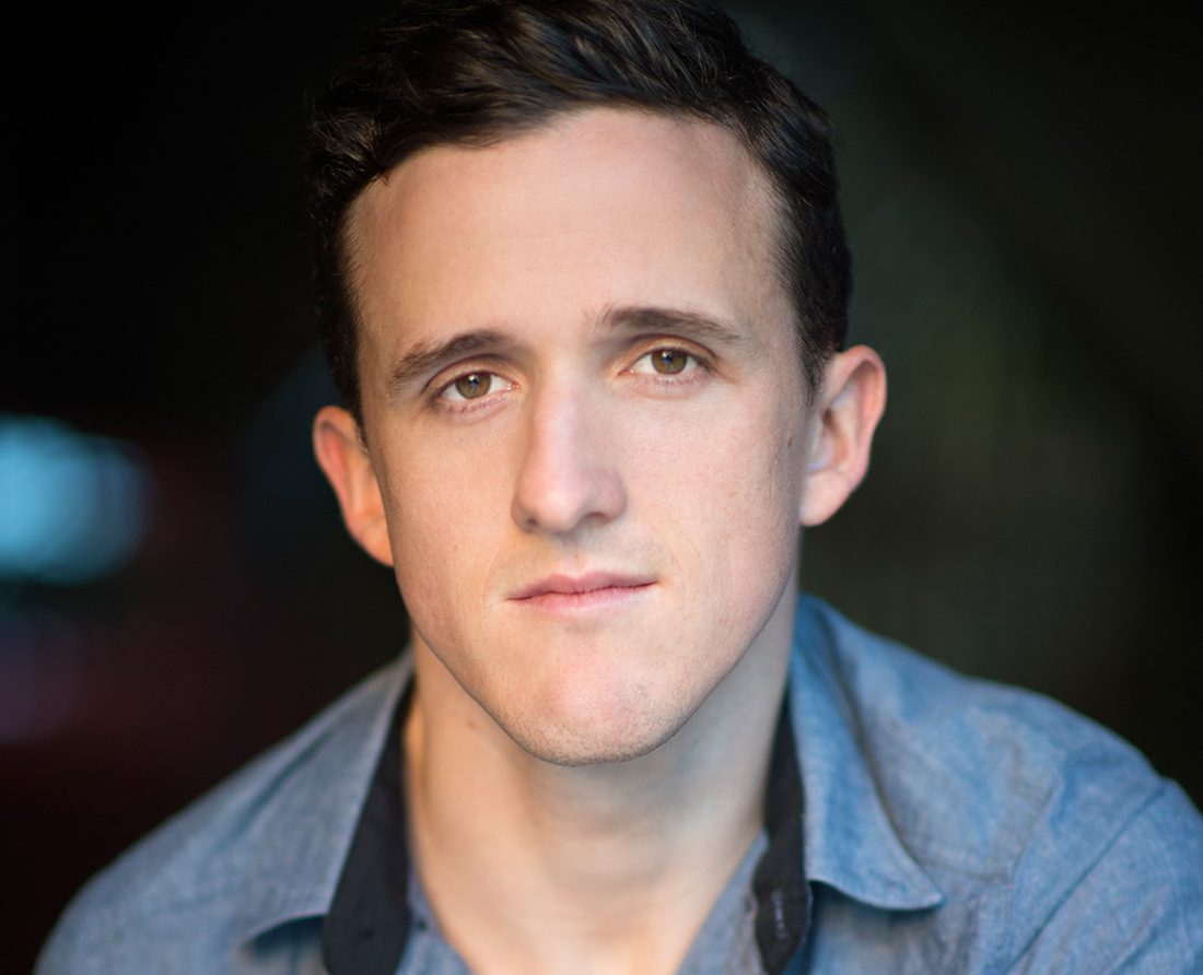 Photographic image of actor and filmmaker Daniel Monks. A man in a shirt against a dark background.