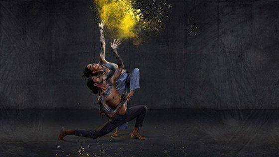 Image is a painting of two people leaning back and looking up at a cloud of colour.