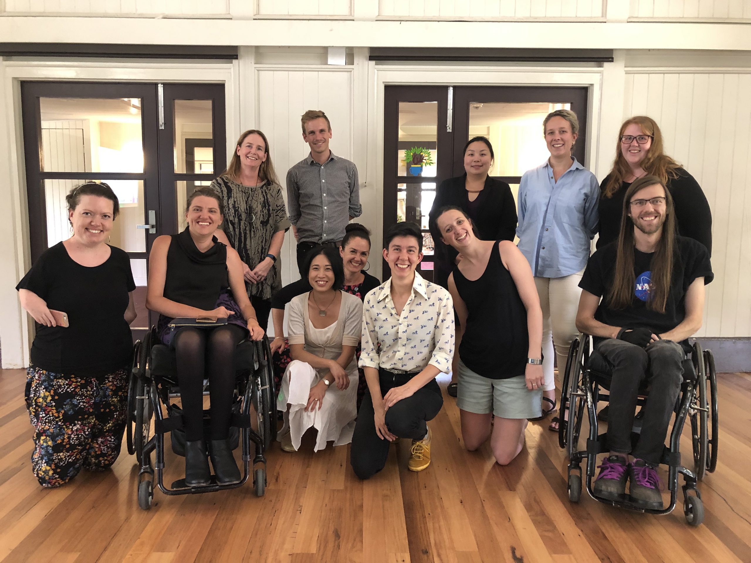 Image shows a group of people in a workplace room. several are wheelchair users