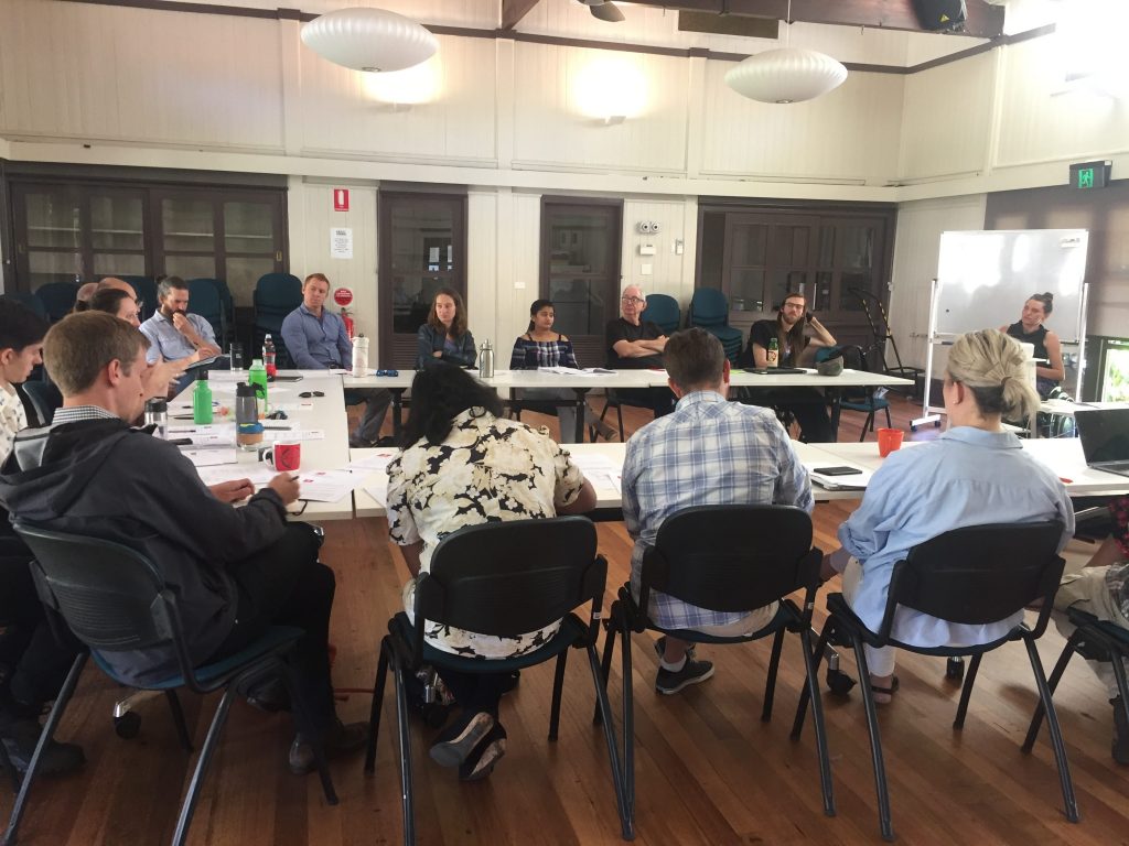 people sitting at desks in a room listening top a presentation from a trainer