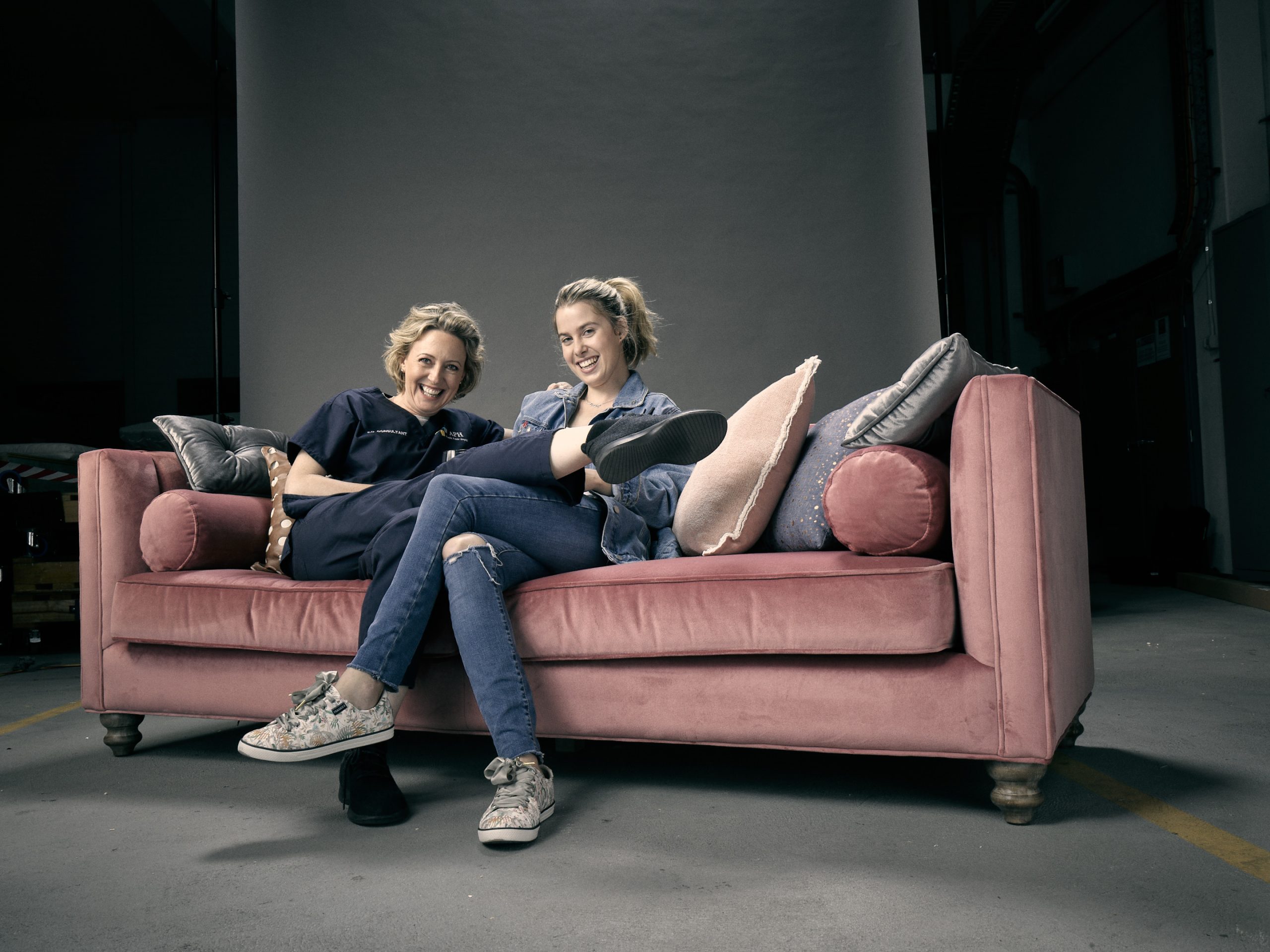 Image shows a photograph of actors Bridie McKim and Roz Hammond on a sofa.