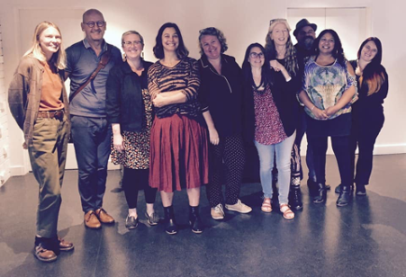 10 people of various ages and cultural backgrounds standing in a line in a white room