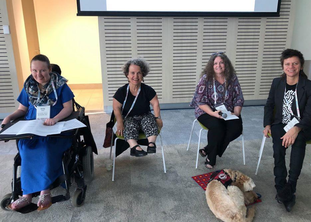 Four women sitting in chairs on a stage