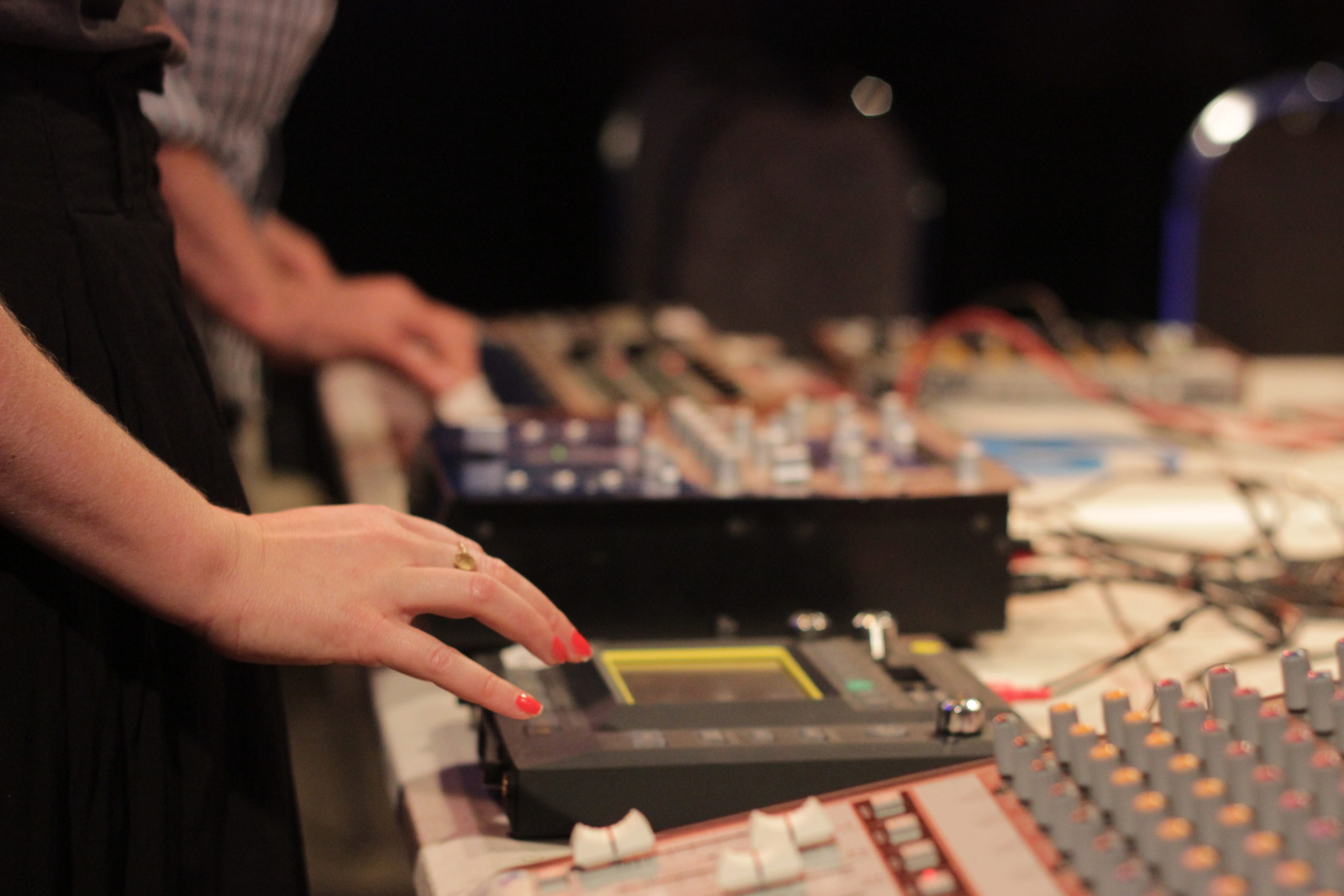 A woman's hands operating devices in a sound recording studio.